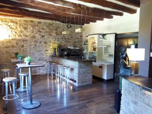 un bar con taburetes en una habitación con una pared de piedra en Molí Blanc Hotel, en Jorba