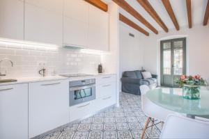 Una cocina con gabinetes blancos y una mesa. en Flateli Rambla 5 3-2, en Girona