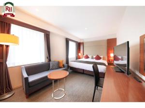a hotel room with a bed and a couch and a tv at Richmond Hotel Tokyo Shiba in Tokyo