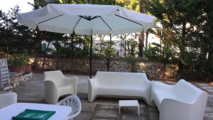 a white table and chairs and an umbrella at Villa Jobè in Polignano a Mare
