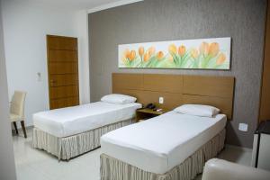 Star Hotel في إيتابيرونا: غرفة فندقية بسريرين ولوحة على الحائط