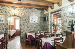 a restaurant with tables and chairs and a stone wall at Hotel Da Giovanna in Chiusi della Verna