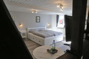 Un dormitorio con una cama y una mesa con una botella. en Pension Gute Stube, en Sulzfeld