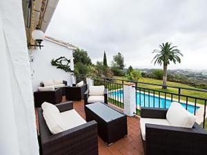 a balcony with couches and a table and a pool at Villa El Capricho in Mijas