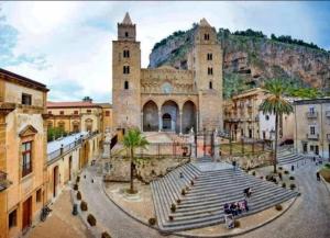 un grand bâtiment avec deux tours et des palmiers dans l'établissement Mansarda Camelie via dei Normanni, 45, à Campofelice di Roccella