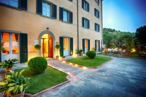 a house with a courtyard with grass and plants at Hotel Villa Marsili in Cortona