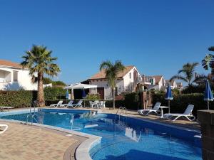 a swimming pool with chairs and palm trees next to a house at Mansarda Camelie via dei Normanni, 45 in Campofelice di Roccella