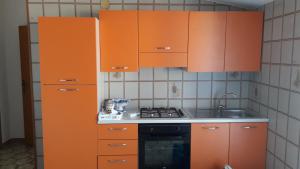 eine Küche mit Orangenschränken und einem Herd in der Unterkunft B&B Maia House in Santo Stefano di Camastra