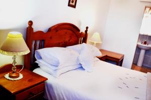 ein Bett mit weißen Kissen und einem Tisch mit einer Lampe in der Unterkunft 54 On Strand in Lambertʼs Bay + 10 Fotos
