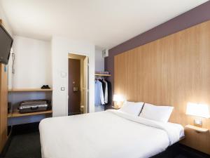 B&B HOTEL Amiens في لونجو: غرفة نوم بسرير ابيض كبير وتلفزيون