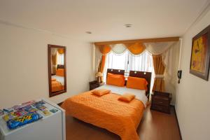 Schlafzimmer mit einem Bett mit orangefarbener Bettwäsche und orangefarbenen Kissen in der Unterkunft Hotel Senegal in Pasto