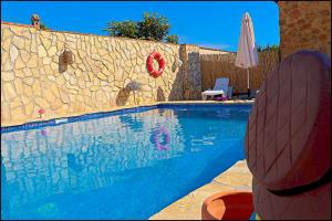 コニル・デ・ラ・フロンテーラにあるApartamento con acceso a piscinaの石壁のスイミングプール(傘付)
