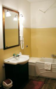 een badkamer met een wastafel, een bad en een spiegel bij Hotel Al Barco in Santo Stino di Livenza