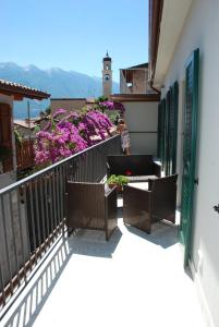 un balcone con tavoli, sedie e fiori viola di Casa Fanny a Limone sul Garda