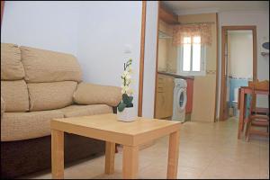 ein Wohnzimmer mit einem Sofa und einem Tisch mit Blumen darauf in der Unterkunft Apartamento centro de Conil in Conil de la Frontera