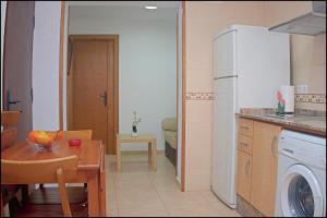 eine Küche mit einem Tisch und einem weißen Kühlschrank in der Unterkunft Apartamento centro de Conil in Conil de la Frontera