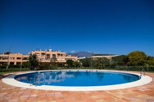 a large blue swimming pool with buildings in the background at Casares del Sol Ground Floor Apartment in Casares