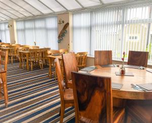 a dining room with tables and chairs and windows at The Beach Motel in Trearddur