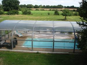 a swimming pool under a glass house with a pool at Tante Pim in Neuilly-sur-Eure