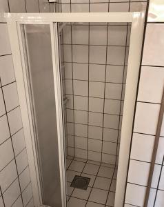 a shower in a bathroom with white tiles at Marifjøra Sjøbuer in Marifjora +45 photos