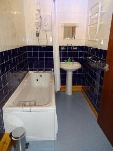 a bathroom with a white tub and a sink at Orkneylodge in Orphir