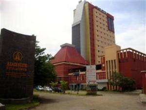 a building with a sign in front of a street at Abadi Suite Hotel & Tower in Jambi