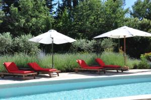 un gruppo di sedie e ombrelloni accanto alla piscina di Le Clos Geraldy - Charming B&B et Spa a Saint-Maximin-la-Sainte-Baume
