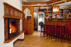 a bar with a fireplace and bar stools at Penzion Vaněk in Velké Losiny