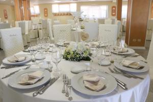 una mesa con platos y vasos blancos y cubiertos en Le camere di Villa Incanto en Colonnella