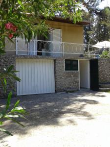 ein Haus mit weißen Garagentüren und einem Balkon in der Unterkunft Holiday Home Paradizo in Veli Lošinj