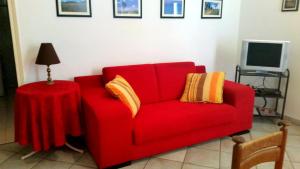 eine rote Couch mit einem Tisch neben einem Fernseher in der Unterkunft Terrasini Siracasa in Terrasini