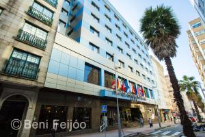 a tall building with a palm tree in front of it at Galicia Palace in Pontevedra