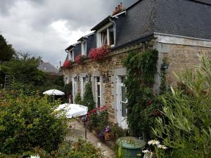 uma casa de pedra com flores ao lado dela em Chambres d'Hôtes l'Hermine em Val Couesnon