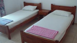 two beds in a room with two tables and towels at Creta Vassakis Studios in Kefalos