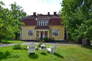 une maison jaune avec deux chaises et une table dans la cour dans l'établissement Villa Baumgartner, à Lovisa