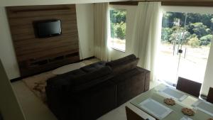 a living room with a couch and a flat screen tv at Mirante de Escarpas 801 in Capitólio