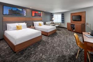 a hotel room with two beds and a television at Studio Inn & Suites at Promenade Downey in Downey