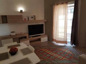 Una sala de estar con un televisor, un sofá y una mesa. en Vittorio Emanuele Appartamenti, en Palermo