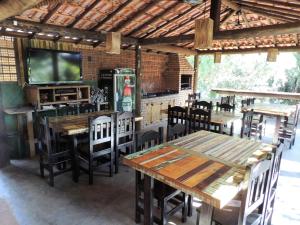 um restaurante com mesas e cadeiras de madeira e uma televisão em Guappo Socorro em Socorro