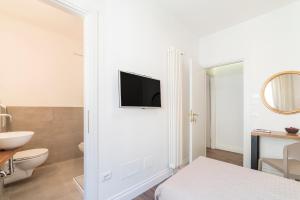 a white bathroom with a toilet and a tv on a wall at Guest Roma House in Rome