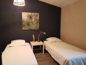 a bedroom with two beds and a table with a lamp at les bignones in Uzès