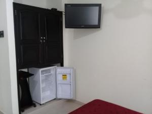 een kamer met een koelkast en een tv aan de muur bij Hotel Dainner in Plato