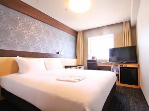 高知市にあるリッチモンドホテル高知の大型ベッドとテレビが備わるホテルルームです。