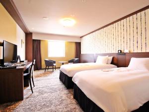 高知市にあるリッチモンドホテル高知のベッド2台とデスクが備わるホテルルームです。
