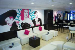 a living room with white couches and a large mural at Mia City Villahermosa in Villahermosa