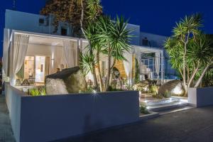a white house with palm trees in front of it at Sea Nymphs Suites in Agia Anna Naxos