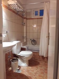 een badkamer met een toilet, een wastafel en een bad bij Parthenon in Ios Chora