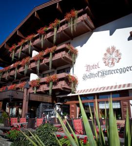 a building with red chairs and potted plants on it at Hotel Gasthof Mitteregger in Kaprun