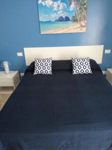 ein blaues Schlafzimmer mit einem großen Bett mit zwei Kissen in der Unterkunft Michelangelo Rooms in Catania