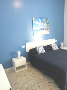 ein Schlafzimmer mit einem Bett und einer blauen Wand in der Unterkunft Michelangelo Rooms in Catania